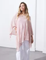 Poncho blanco de tejido calado con lurex, terminación asimétrica y cuello redondo.