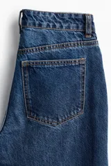 Pantalón de jean azul de corte acampanado, con tiro medio y cinco bolsillos.