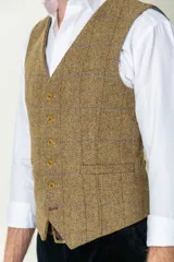 Chaleco de tweed marrón con diseño a cuadros, cierre frontal con botones dorados y dos bolsillos delanteros.