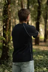 Remera negra de manga corta raglán, confeccionada en algodón. Presenta costuras a la vista y calce relajado.