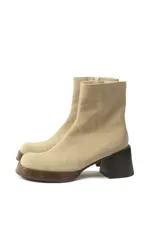 Bota corta de gamuza color beige claro, con caña ajustada y taco cuadrado de madera oscura.