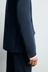 Blazer slim fit azul marino confeccionado en tejido con viscosa. Cuello con solapas de muesca, manga larga con puño abotonado, bolsillo de vivo en pecho y de solapa en cadera, bolsillo interior, bajo con aberturas en espalda y cierre frontal con botones.