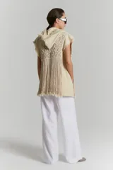 Chaleco largo color beige de tejido rústico de algodón con macramé aplicado y capucha. Terminaciones al corte, desflecadas.