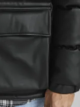 Campera puffer negra de poliéster con cuello alto, cierre frontal con cremallera, bolsillos laterales con solapa y puños elásticos.