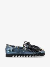Zapato náutico plateado con flecos y cordones negros, y suela track negra.