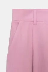 Pantalón negro de tiro alto con corte palazzo, bolsillos laterales y pliegues frontales. Cierre frontal con cremallera y botón.