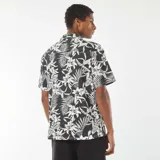 Camisa de manga corta con estampado de flores y hojas en blanco y negro, con cuello solapa y cierre frontal con botones de madera.