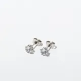 Par de aros tipo stud (perno) con piedra de circones redonda engastada en metal plateado.