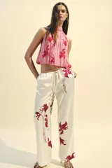 Top sin mangas color rosa con estampado de flores rojas, cuello halter y espalda descubierta.