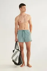 Short de baño de sirsaca a rayas verticales verdes y blancas, con aberturas laterales cortas, elástico y cordón ajustable en la cintura, bolsillos laterales, bolsillo trasero con cierre autoadherente y suspensor interior de malla.