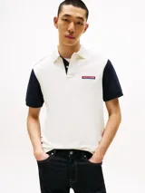 Chomba Tommy Hilfiger de hombre con diseño color block en blanco y azul marino. Tiene cuello tipo chomba, cartera de dos botones y logo bordado en el pecho.