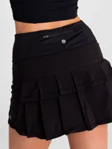 Falda deportiva negra con calza interior, de secado rápido. Diseño acampanado con plisado en la parte trasera, pretina ancha con bolsillo con cierre y bolsillo interior en la calza.