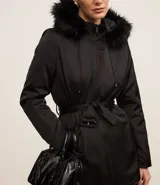 Campera parka negra con cuello alto, capucha con borde de piel sintética, cierre frontal con cremallera, bolsillos con cremallera y cinturón con hebilla.