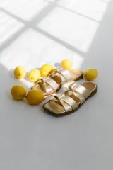 Sandalias bajas color camel con tiras anchas entrelazadas formando un nudo.