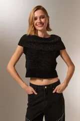 Chaleco negro de tejido de punto con lurex, cuello alto y sin mangas.