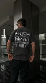 Remera negra nevada de corte oversize con estampado en la espalda con la palabra "Introvert" y diferentes íconos y textos.