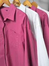 Camisa blanca de manga larga con cuello clásico y botones frontales.