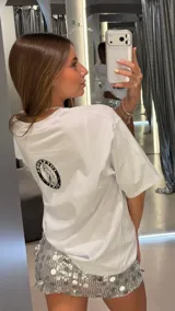 Remera blanca de algodón, corte oversize, con estampa fotográfica en blanco y negro de una mujer con cabello largo y accesorios.