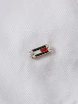 Camisa blanca de algodón orgánico con corte regular, cuello mao con volantes, cierre frontal con botones, mangas largas con puños abotonados y logo bordado en el ruedo.