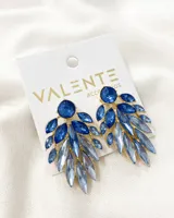 Par de aros colgantes con base dorada y múltiples piedras facetadas en tonos de azul.