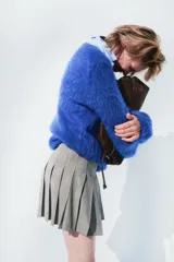 Pollera corta con pliegues marcados (tableada) y silueta evasé. Presenta un estampado de pata de gallo o príncipe de Gales en tonos grises y blancos.