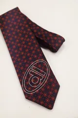 Corbata de seda color rojo con estampado de micro lunares y logo de la marca serigrafiado en blanco.