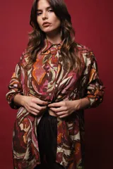 Camisa de seda de algodón estampada con arabescos en tonos marrones, verdes, naranjas y dorados. Tiene corte holgado, abertura frontal y lurex dorado.