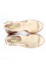 Sandalia de mujer color beige con puntera abierta y tira en forma de T. Posee tira de ajuste con hebilla en el tobillo y detalle de cuero metalizado plateado en el talón. El taco es ancho y de madera.