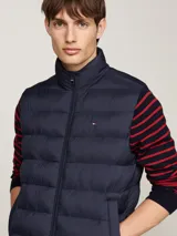 Chaleco acolchado Tommy Hilfiger color azul marino, con cuello alto, cierre de cremallera y dos bolsillos laterales.