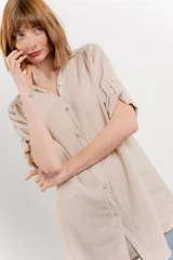 Camisa amarilla de lino con corte recto y calce suelto. Tiene cuello camisero, botones en el frente y mangas cortas con presilla y botón.