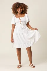 Vestido corto blanco con escote bardot, cintura fruncida y falda escalonada con vuelo.