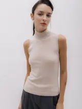 Top de punto color beige, sin mangas y con cuello alto.