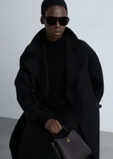 Vestido midi negro de tejido de punto fino, con cuello alto y manga larga. Diseño recto y terminaciones en canalé.