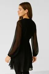 Vestido corto negro de poliéster con cuello polera, mangas abullonadas y falda con volados.
