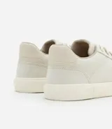 Championes color beige con puntera redonda, caña corta, cierre por cordones y detalle en recortes.