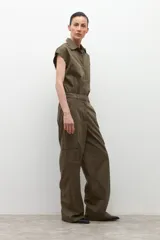 Mono de color verde oliva con cuello camisero, cierre frontal de botones y bolsillos tipo cargo. Presenta mangas cortas y cintura marcada.