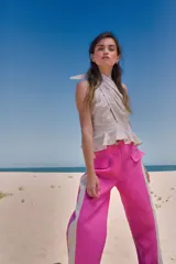 Pantalón de lino color fucsia, de tiro medio y corte holgado, con bolsillos laterales y franja vertical color crema en los laterales.