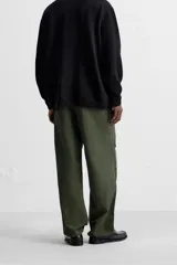 Pantalón verde militar de corte relaxed fit confeccionado en tejido técnico ligero. Cuenta con cintura elástica ajustable con cordón interior, bolsillos frontales y traseros con solapa, pliegues en las rodillas y bajo ajustable con elástico.