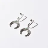 Aros colgantes plateados con forma de media luna texturizada y detalle de piedra verde.