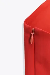 Top rojo de escote recto y hombros descubiertos, con corte peplum y cierre lateral con cremallera oculta.