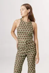 Top corto tipo crop top, sin mangas y con cuello halter. Presenta un estampado grande de flores en tonos verde claro, verde azulado y beige/crema.