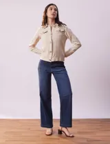Campera color beige de algodón con cuello camisero, abertura central con botones de madera, bolsillos de parche en el pecho y mangas largas con puños abotonados.