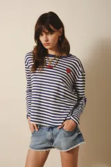Remera de manga larga confeccionada en algodón a rayas horizontales azul marino y blanco. Tiene un pequeño bordado de corazón rojo en el frente y cuello redondo.
