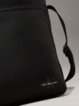 Cartera de piel sintética suave color negro, con monograma distintivo y cierre de cremallera en la parte superior.