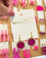Aros colgantes con forma circular, con centro fucsia y borde de strass plateados. El aro es de acero dorado.