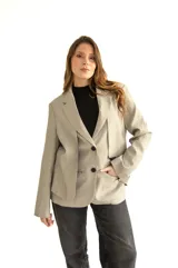 Blazer gris de silueta recta y textura sutil, con solapas de muesca, cierre con dos botones, bolsillos con solapa y puños con cuatro botones.