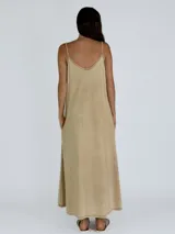 Vestido largo color crudo, de breteles finos y escote en V, con volantes verticales en el frente y bolsillos laterales.