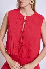 Blusa sin mangas color azul marino, con cuello redondo y detalle de tablas verticales en el frente. Corte corto con terminación fruncida y lazos ajustables en el escote.