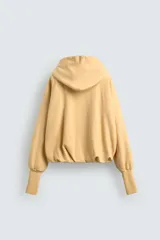 Sudadera color amarillo pálido con capucha ajustable con cordones negros, corte holgado, mangas largas con puños acanalados, bajo abullonado y bolsillo tipo canguro. Edición especial Harry Lambert for Zara x Disney.
