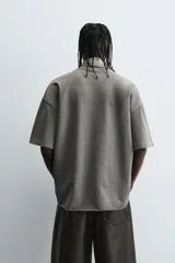 Camiseta color beige de corte holgado, cuello redondo y manga corta.